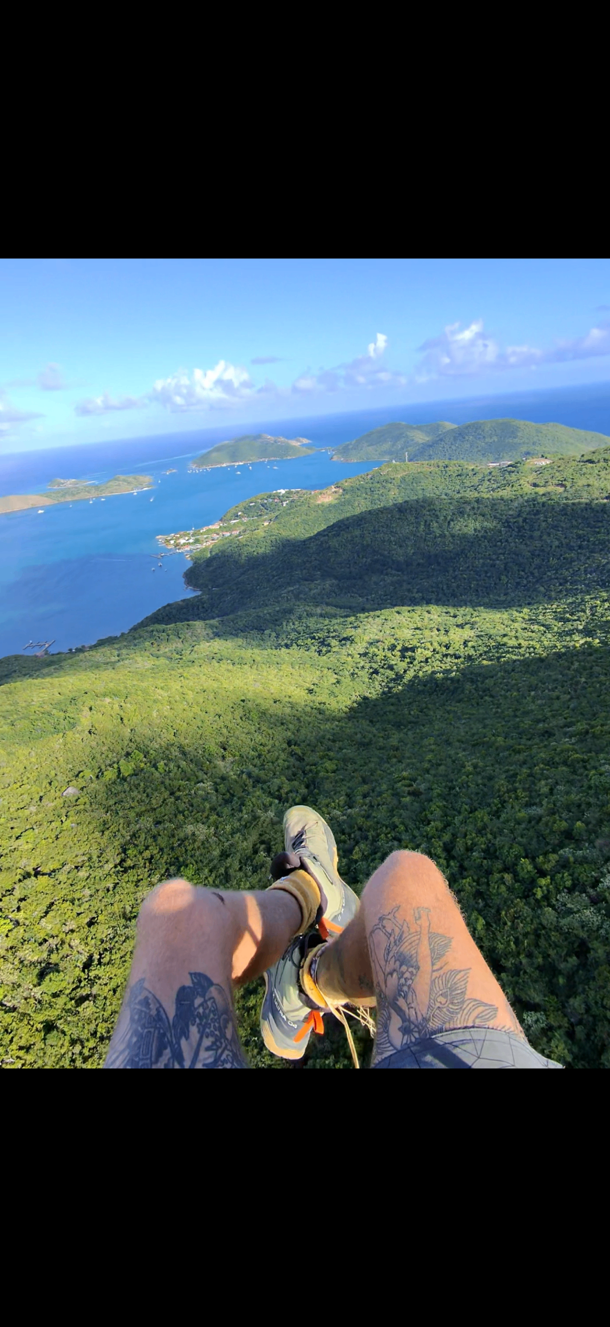 Feet-dangling view from a paraglider harness above Virgin Gorda's North Sound